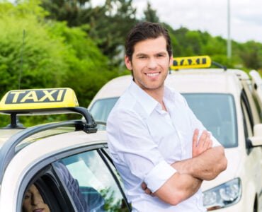 Driver in front of taxi waiting for clients